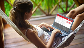 Woman in hammock looking at our regular savings calculator on her laptop