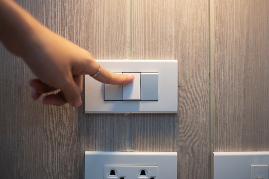 a finger turning off a light switch on the wall