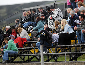 Crowd of people sat on the stands at the side of the TT course