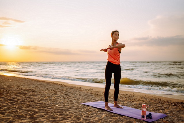 woman doing sunset yoga on the beach